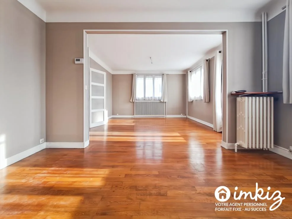 Séjour lumineux avec parquet bois et double ouverture vers la pièce voisine